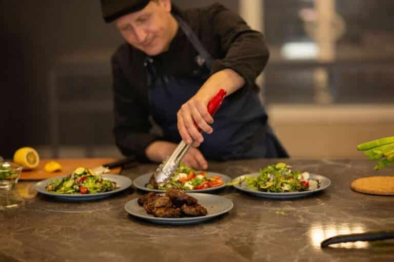 Private chef plating fresh salads and grilled dishes for a group dinner