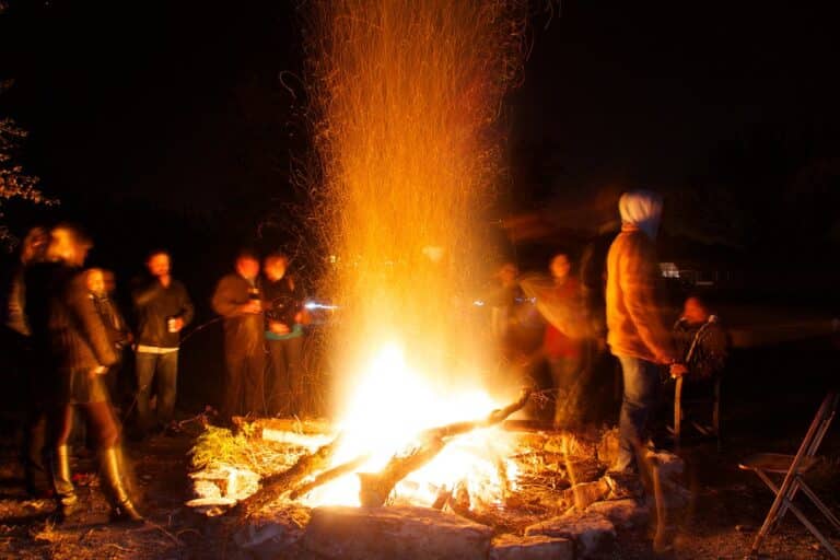 Large group gathered around a campfire at night, the kind of gathering possible when booking both homes in Lake Harmony