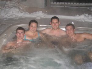 Friends relaxing in an outdoor hot tub in the snow, like the hot tub and game room evenings at our Lake Harmony homes