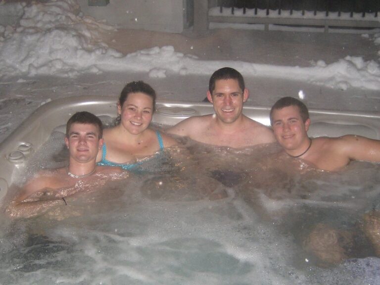 Friends relaxing in an outdoor hot tub in the snow, like the hot tub and game room evenings at our Lake Harmony homes