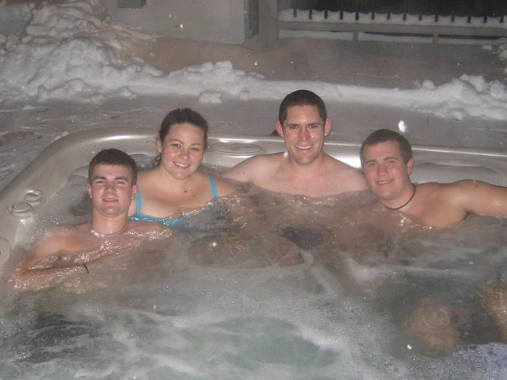 Friends relaxing in an outdoor hot tub in the snow, like the hot tub and game room evenings at our Lake Harmony homes