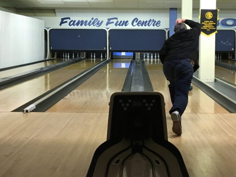 A bowler rolling a ball down the lane