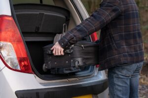 Suitcase being loaded into a car, following a packing list for a group trip to Lake Harmony